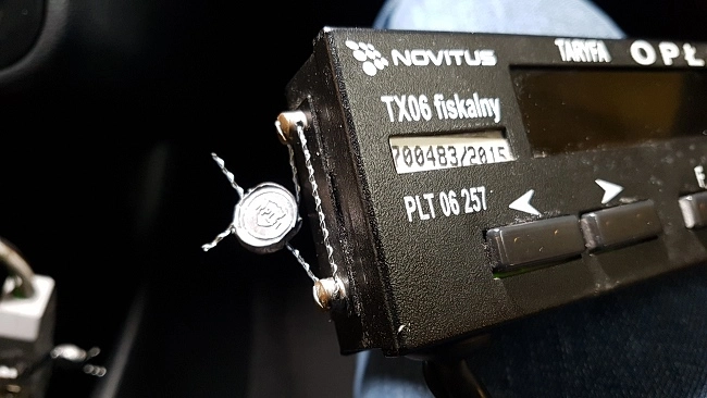 Zdjęcie przedstawia taksometr Novitus TX06 w trakcie sprawdzania w trakcie legalizacji ponownej w pojeździe bez wymontywowania urządzenia